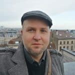 Daniel Schukovitz mit Mütze und Mantel schaut in die Kamera, im Hintergrund Häuserdächer